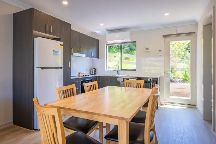 Apartment kitchen and dining area with a timber table and a door out to the garden