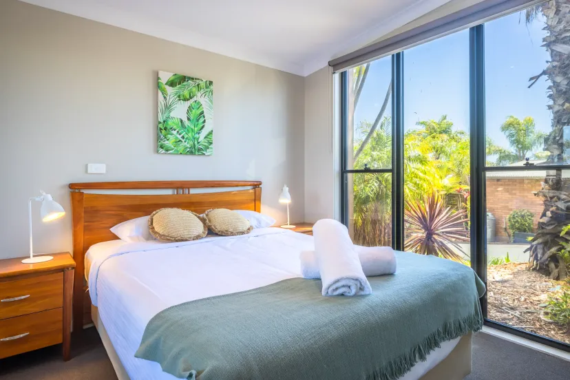 Queen bedroom with a floor-to-ceiling window looking onto the garden