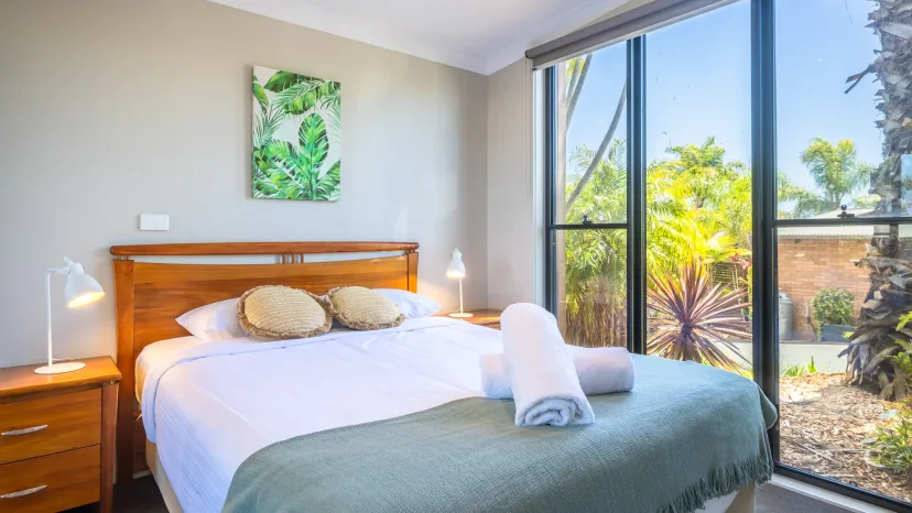 Queen bedroom with a floor-to-ceiling window looking onto the garden