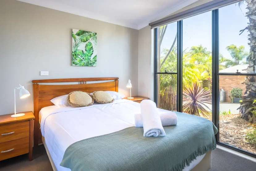 Queen bedroom with fish artwork above the bed and a garden outlook