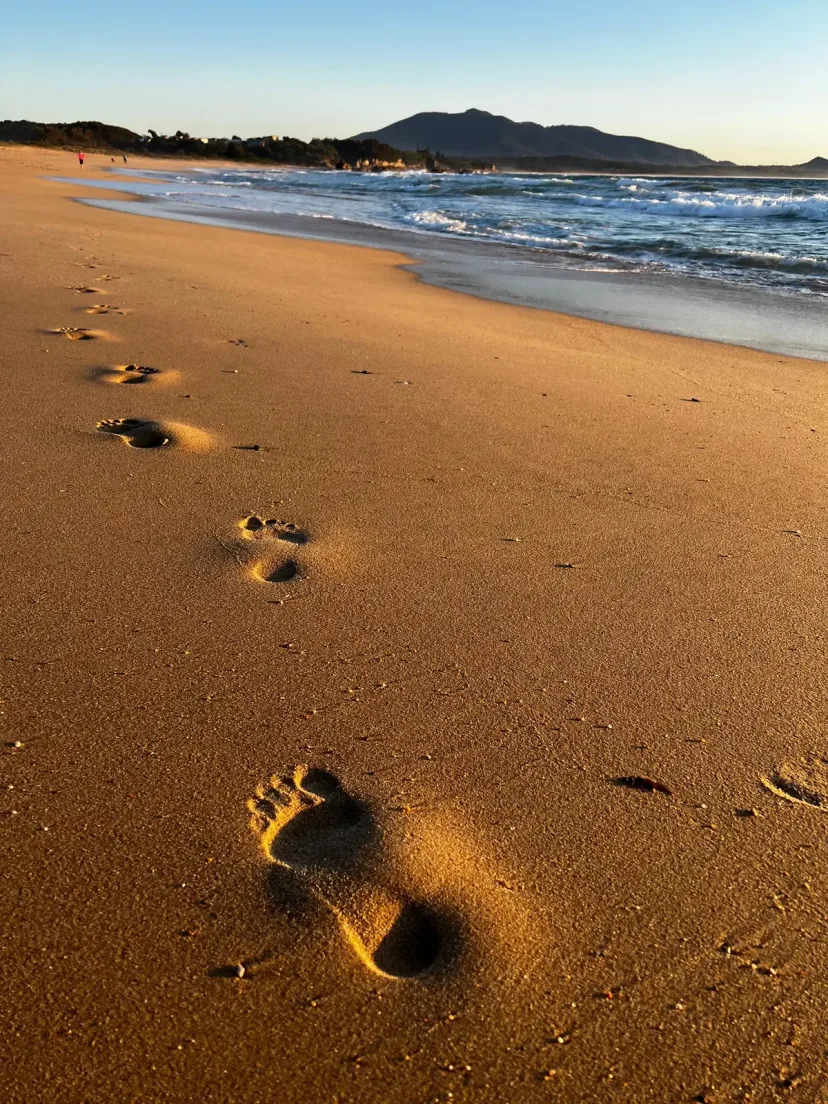 Footprints leading across soft golden sand