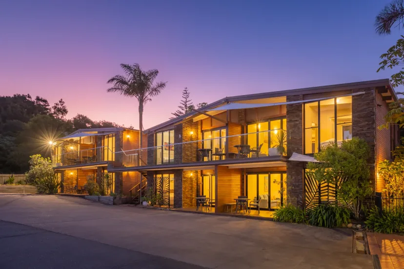 The apartment buildings lit warmly at dusk, framed by palms