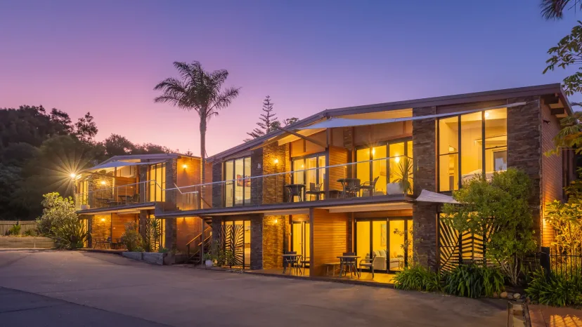 The apartment buildings lit warmly at dusk, framed by palms