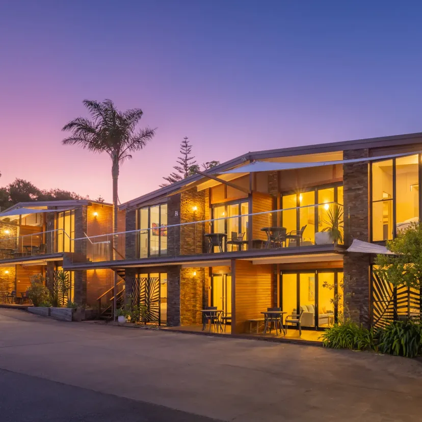 The apartment buildings lit warmly at dusk, framed by palms