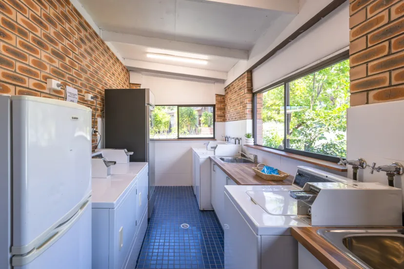 The communal guest laundry with coin-operated washing machines, dryers, sinks and the bait freezer
