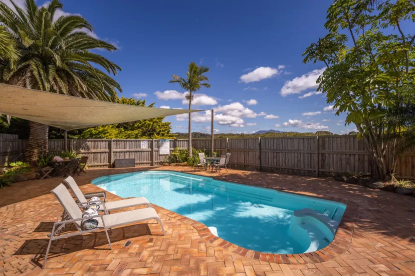 The swimming pool with sun loungers and palms around the paved surround