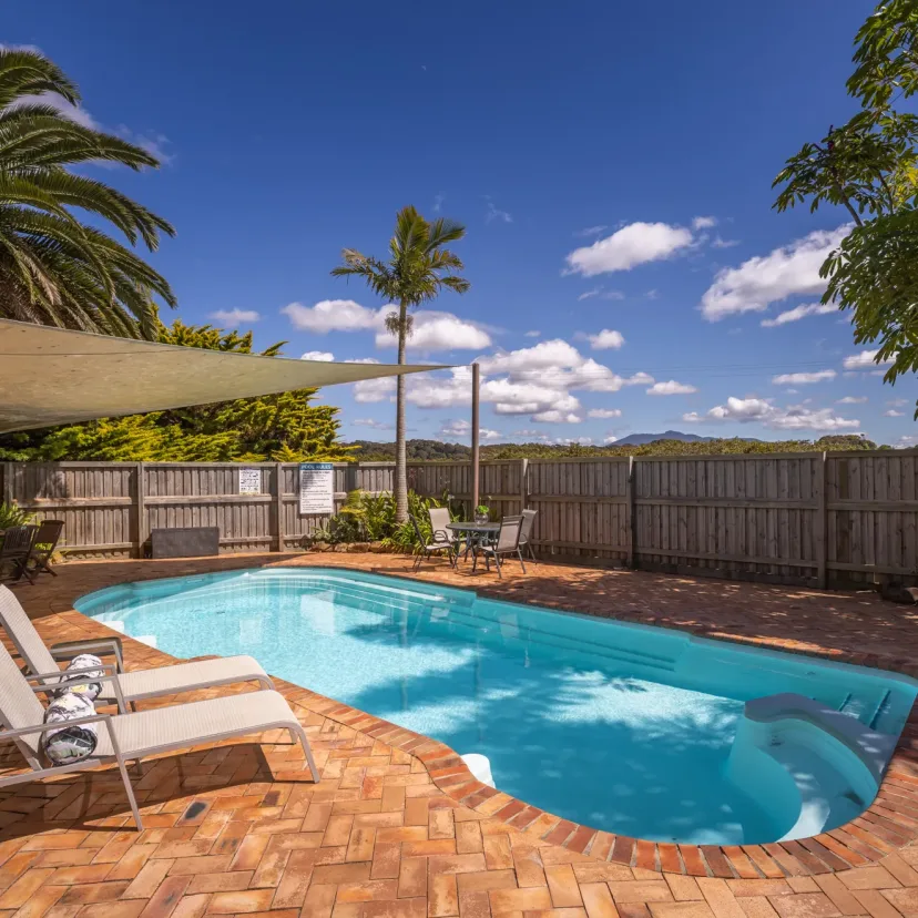 The swimming pool with sun loungers and palms around the paved surround