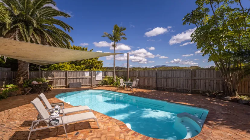 The swimming pool with sun loungers and palms around the paved surround