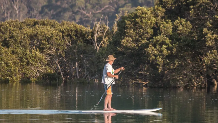 A stand-up paddleboarder on the calm water of the Bermagui River