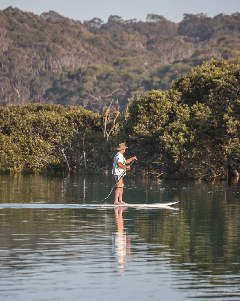 A stand-up paddleboarder on the calm water of the Bermagui River