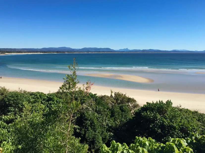 A wide beach and headland on the Sapphire Coast, seen from above the treeline