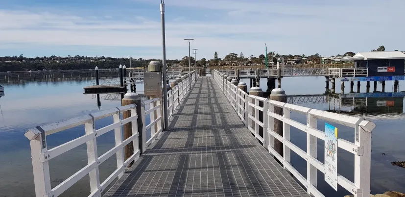 A timber jetty reaching out towards moored boats