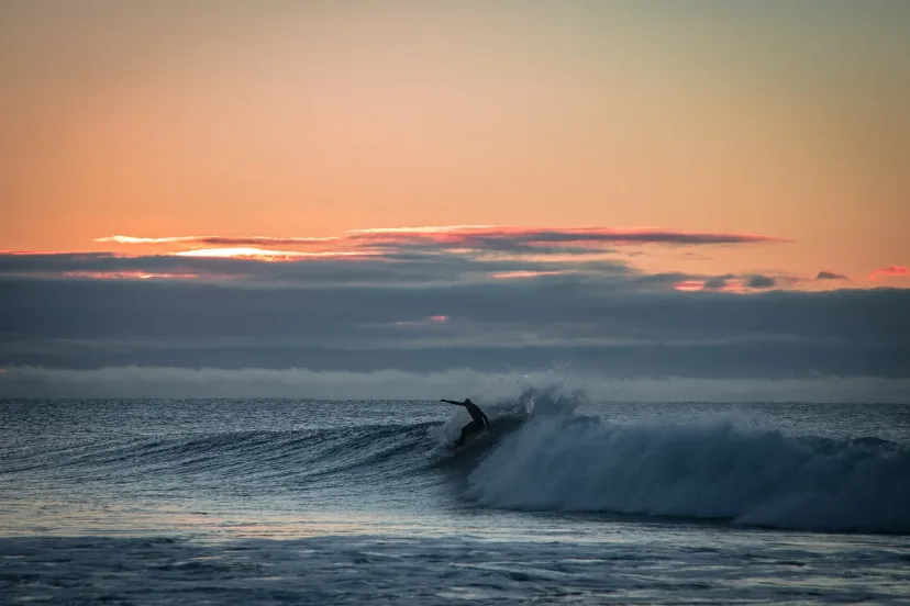 A surfer riding a wave at dawn