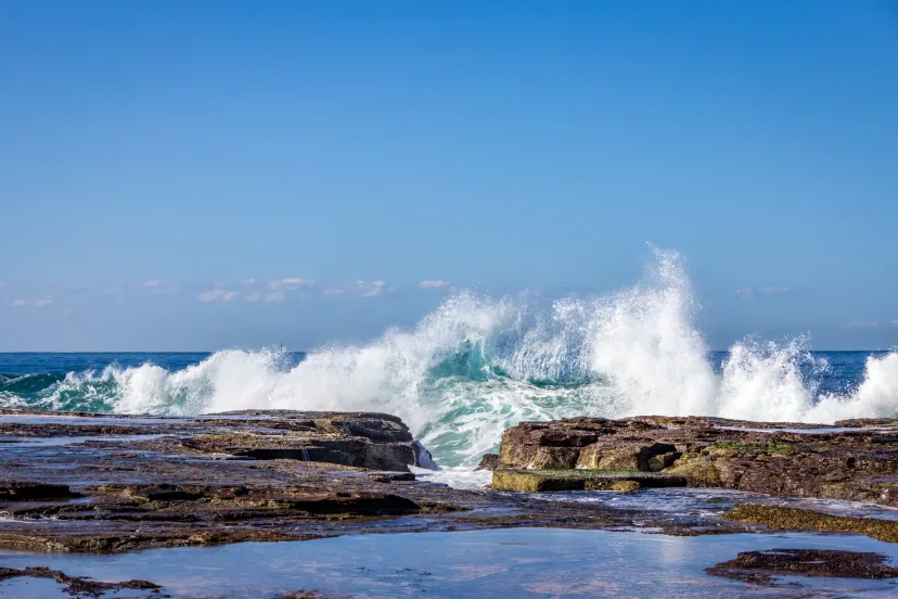 Waves breaking across a flat rock shelf on the coast
